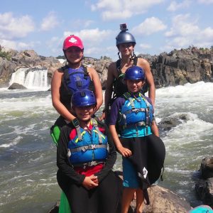 a group of people sitting on a rock near the ocean