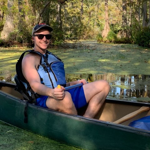 a man on a canoe in a swamp