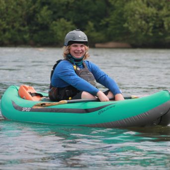a little girl riding on the back of a boat in the water