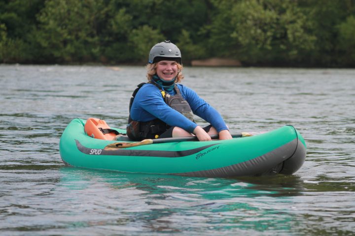 a little girl riding on the back of a boat in the water