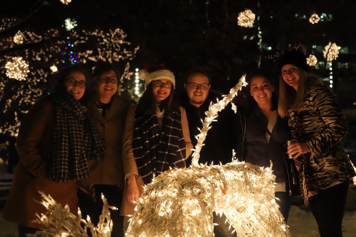 a group of people standing in front of a birthday cake with lit candles