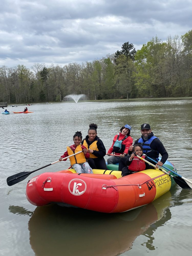 A family smiling and enjoying a ride on a whitewater raft. 